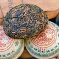 Close-up of a raw pu-erh compressed tea ball on a stack of similar tea balls 