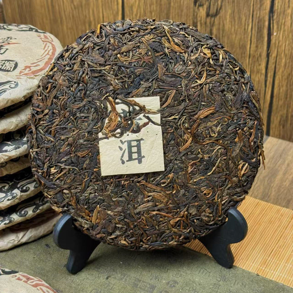 Round tea cake with a label on a stand against a wooden background