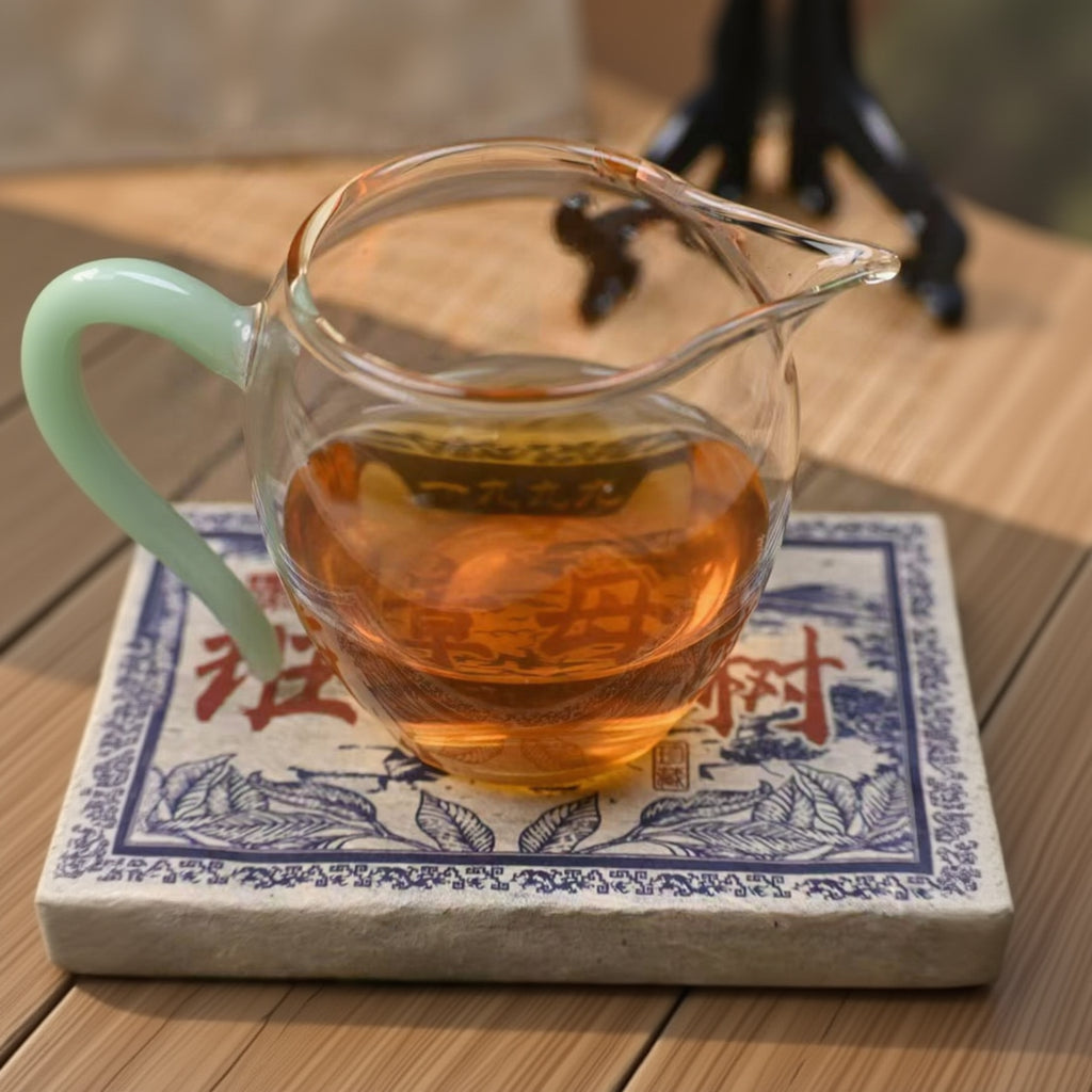 Clear glass teapot with tea on a decorative mat