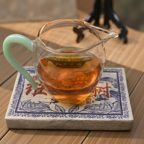 Clear glass teapot with tea on a decorative mat