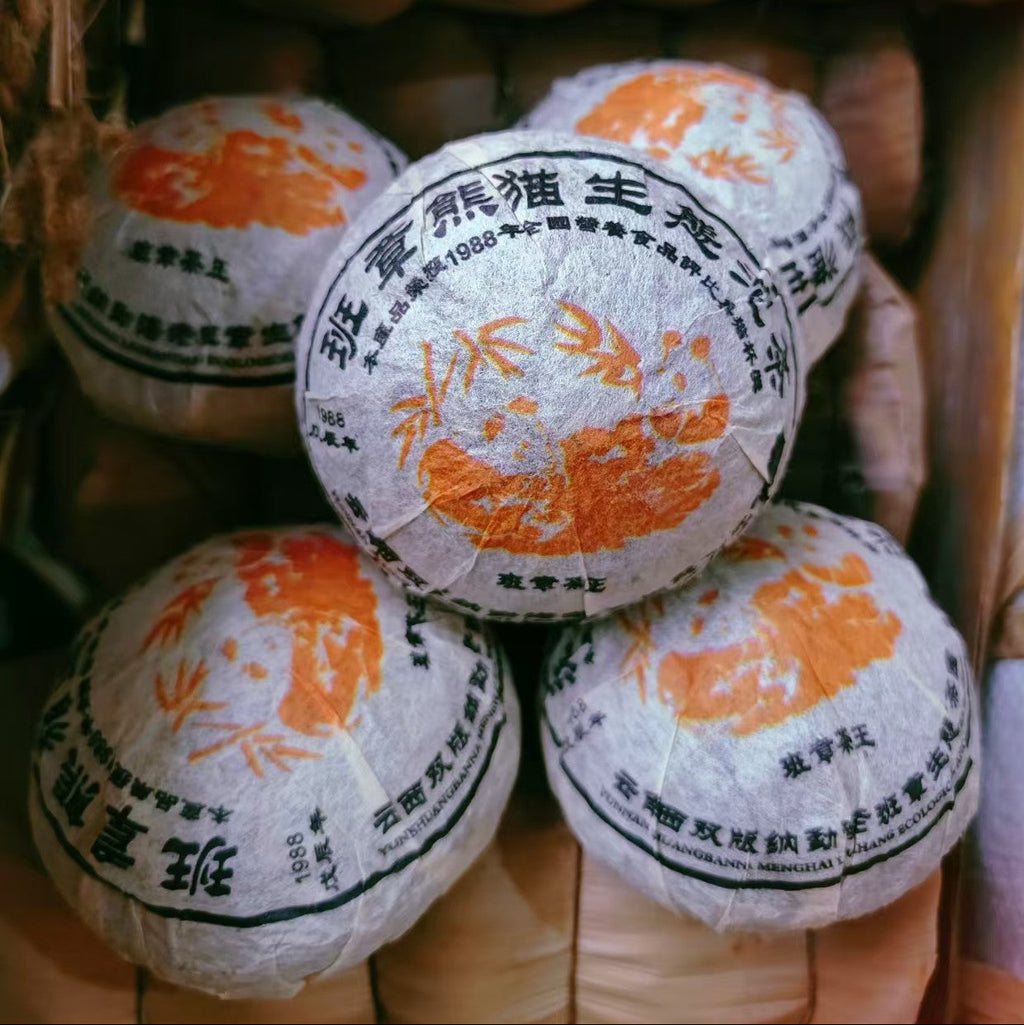 Raw pu-erh Tea cake balls with orange and black design on a woven surface